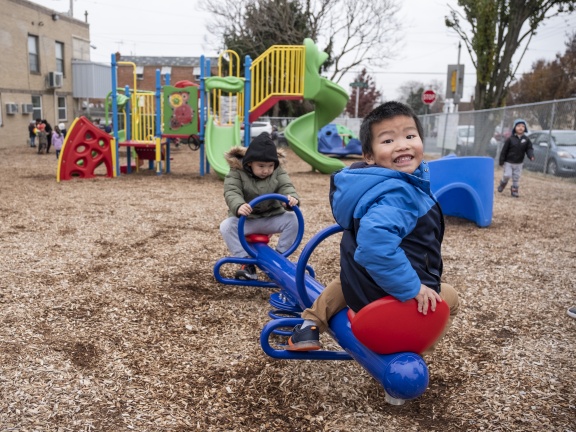 Two little boys on a playground playing on a see-saw.
